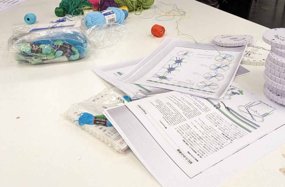 A photograph of instructional print-outs alongside threads on a table as part of a workshop